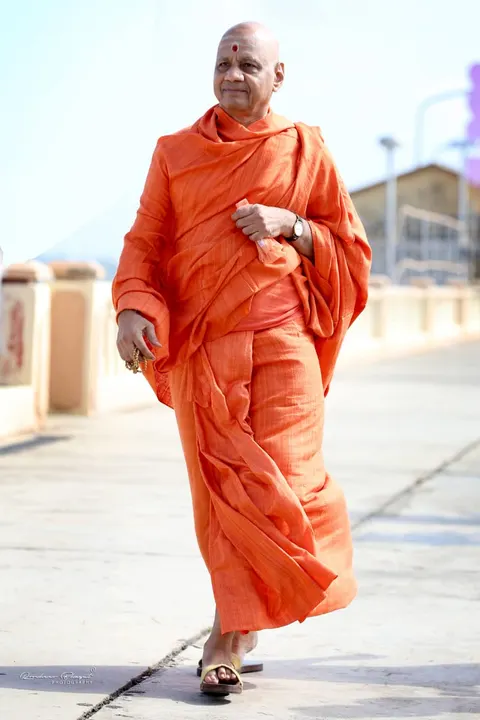 प. पू. स्वामी गोविन्ददेवगिरि जी महाराज भगवा वस्त्रों में हाथ में रुद्राक्ष माला लिए चलते हुए।